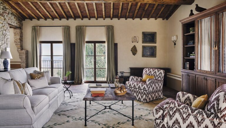 Castello di Casole Suite living room with beamed ceiling, sofas and doors to a terrace, Castello di Casole