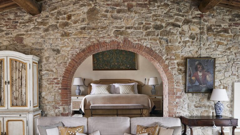 Castello di Casole Suite bedroom set in a brick arch within a stone wall, Castello di Casole