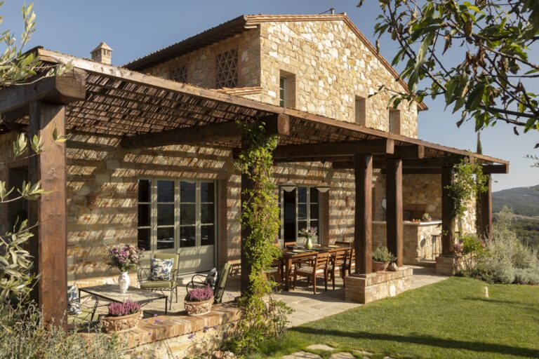 Villa Thesan stone exterior with a pergola terrace and outdoor dining table, Castello di Casole