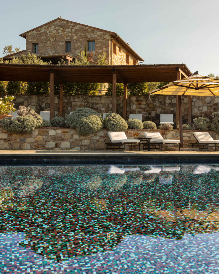 Villa Thesan mosaic-tiled pool with loungers below the stone house, Castello di Casole