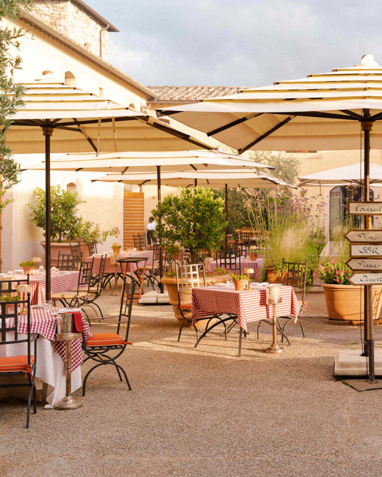 Tosca terrace with umbrellas and tables laid with red gingham cloths, Castello di Casole