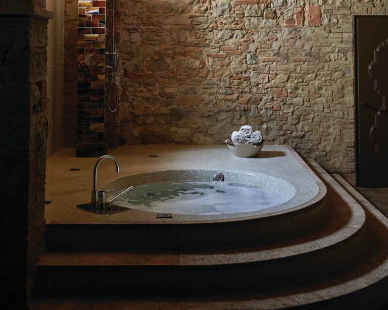 Essere Spa stone-walled room with a round mosaic tub, Castello di Casole
