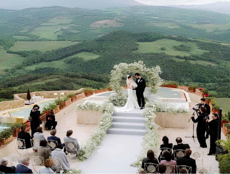 A wedding ceremony on a panoramic terrace, with a floral arch and the valley below, Castello di Velona Resort