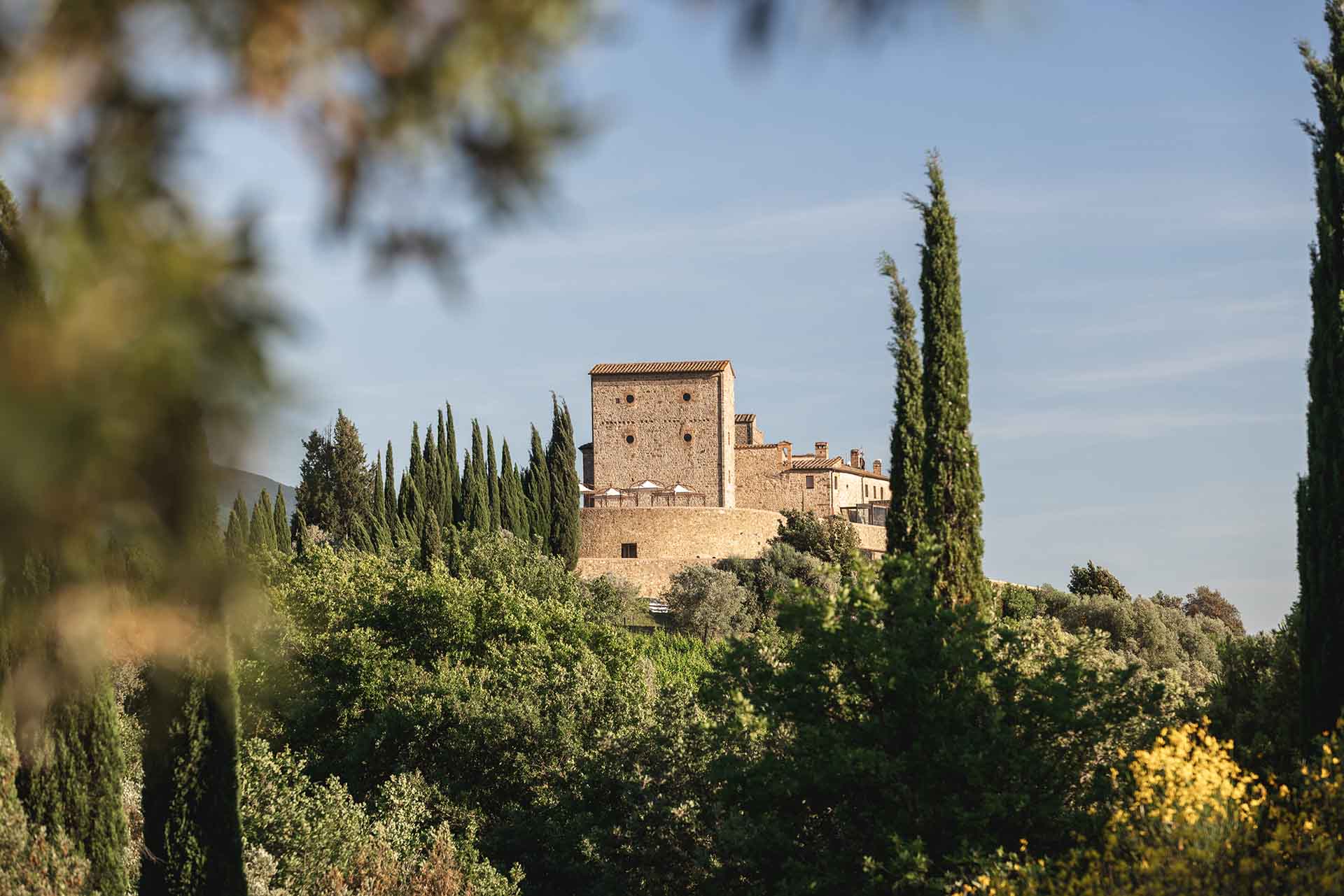 The castle tower framed by cypresses and broom, Castello di Velona Resort