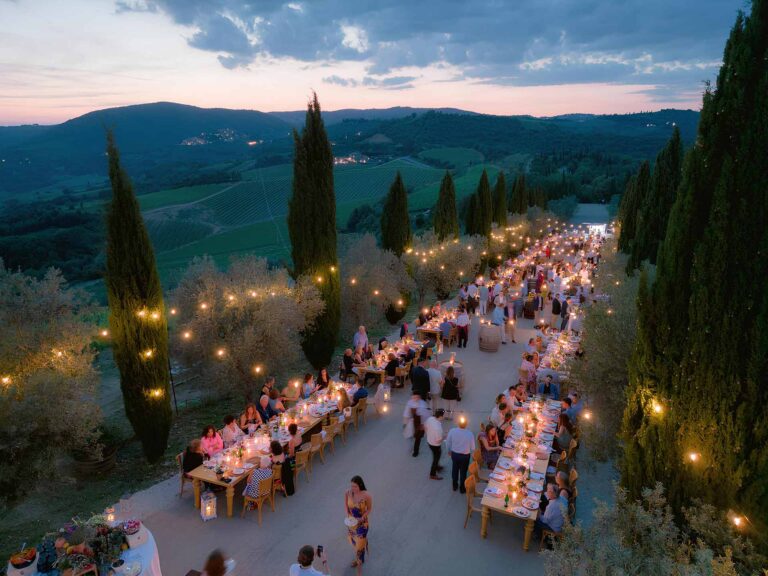 Long dinner tables with festoon lights among the cypresses and olives, Castello di Velona Resort
