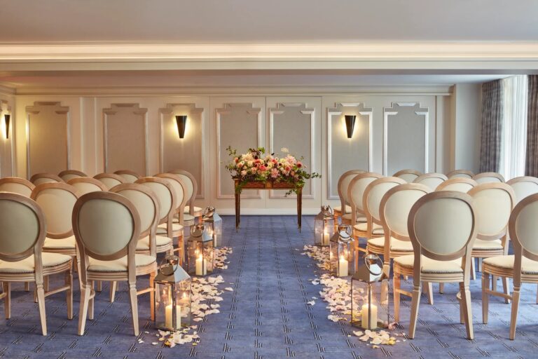 The Clarence Room set with rows of cream chairs, petals and candles along the aisle, Claridge's