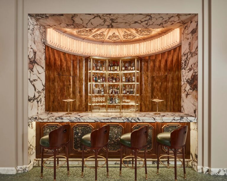 A curved bar counter with leather stools framed in marble and polished wood, Claridge's