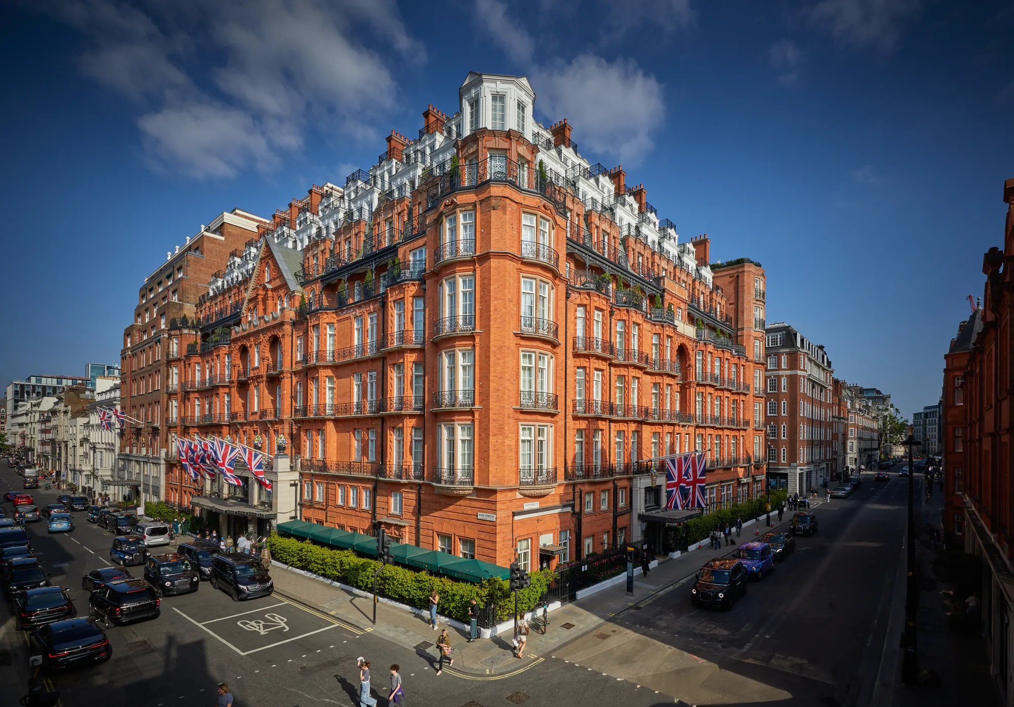 The red-brick corner of the hotel on Brook Street and Davies Street, with flags above the canopy, Claridge's