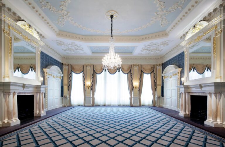 The empty Drawing Room with its fireplaces, blue carpet and chandelier, Claridge's