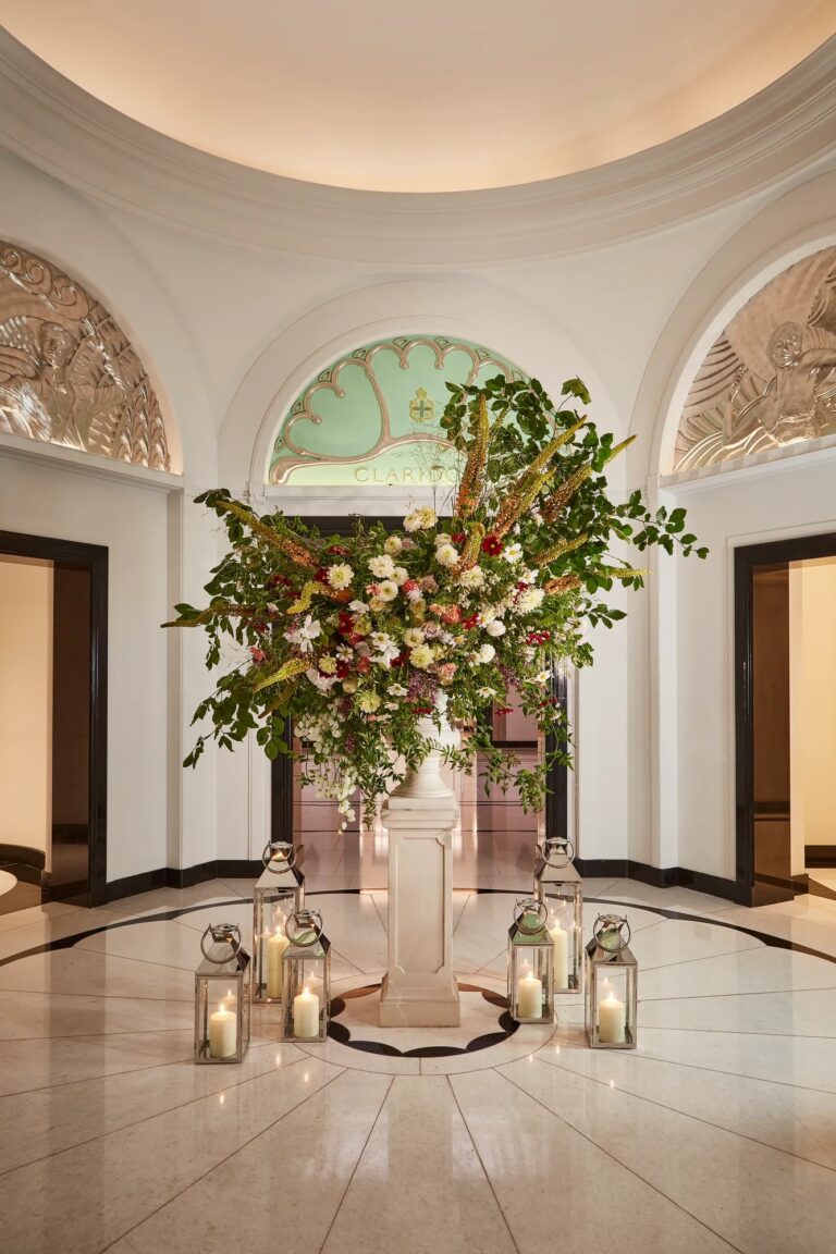 A tall floral arrangement and lanterns in the round Ballroom Reception, Claridge's
