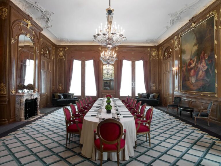 A long dinner table with red chairs in the wood-panelled French Salon, Claridge's