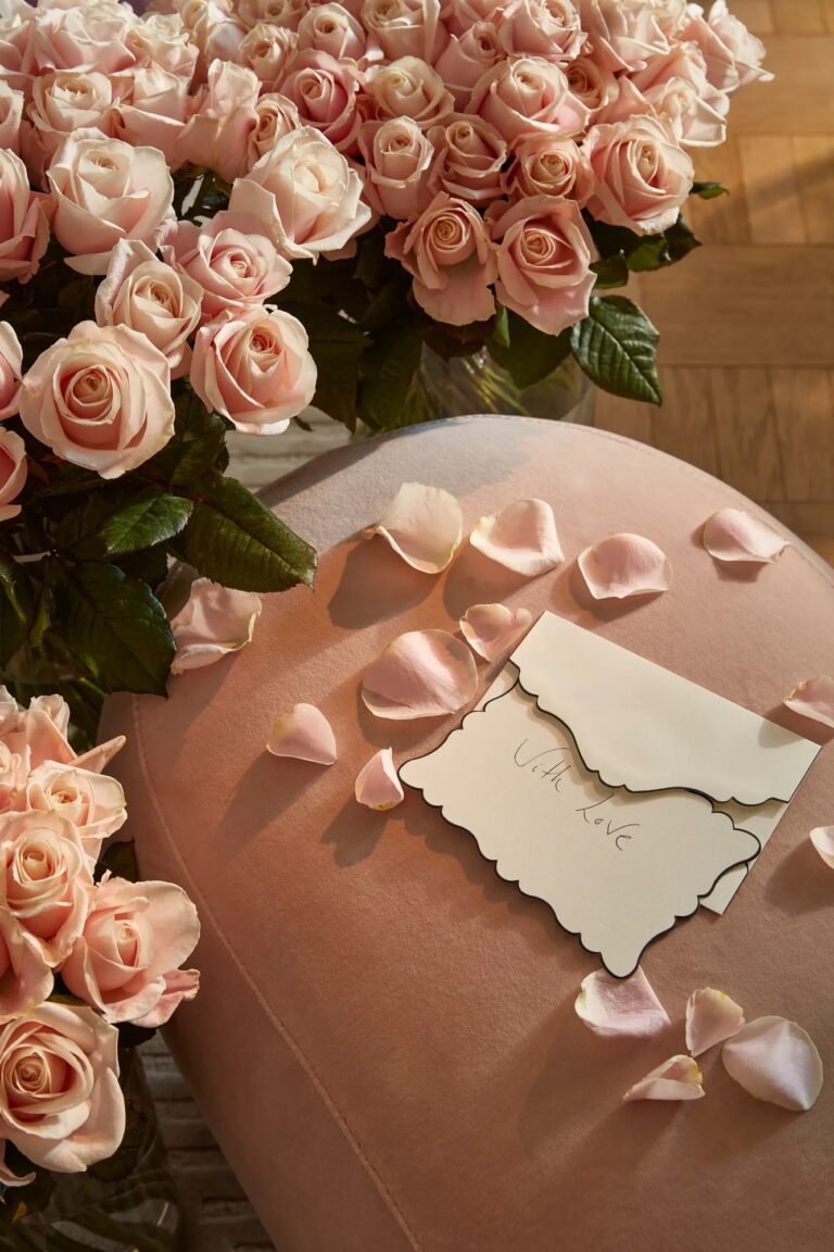 Pink roses and scattered petals beside a handwritten card, Claridge's