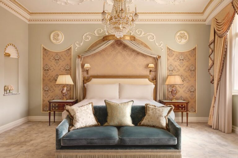 A bedroom in the Royal Suite with a canopied headboard and a velvet sofa at the foot of the bed, Claridge's