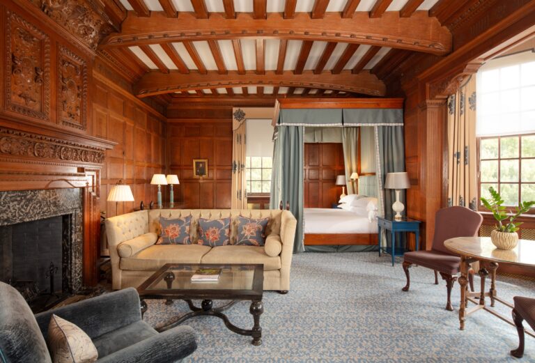 A panelled Deluxe Suite with a four-poster bed, fireplace and sitting area, Cliveden House