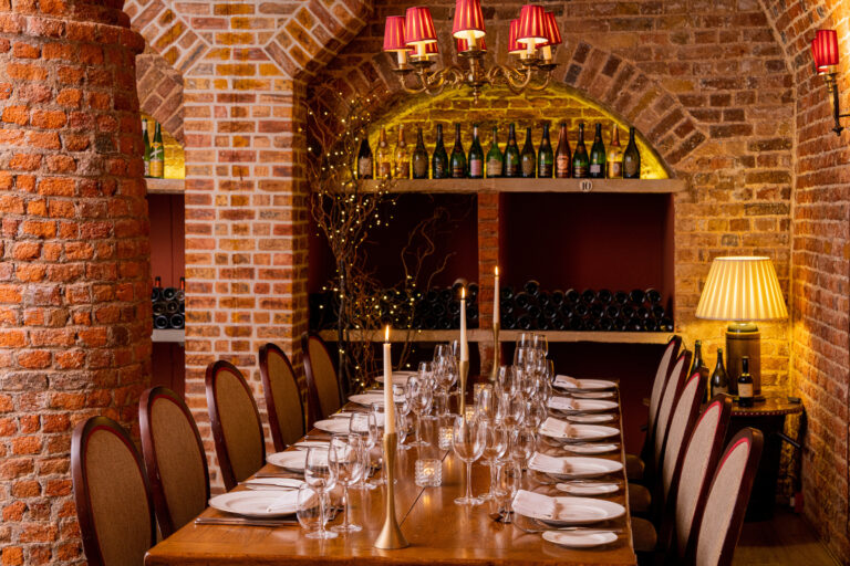 The vaulted brick Cellar Dining Room, laid for a candlelit dinner beside the wine racks, Cliveden House