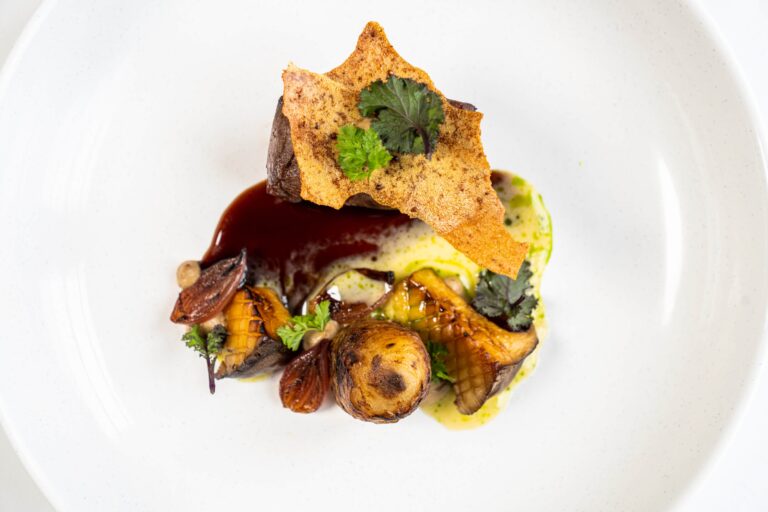 A plated venison dish with roasted vegetables and a crisp garnish, Cliveden House