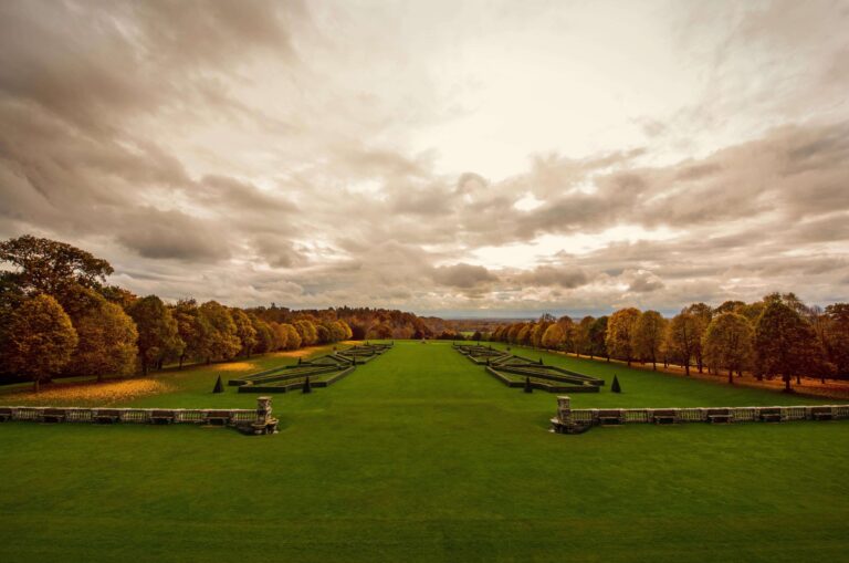 The long lawns and clipped beds of the Parterre in autumn, framed by trees in full colour, Cliveden House