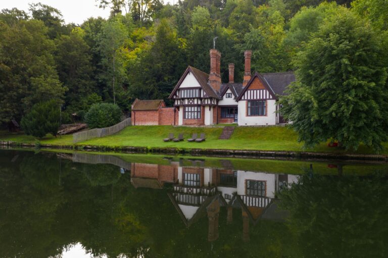 Spring Cottage, a timbered riverside cottage on the estate, reflected in the Thames, Cliveden House