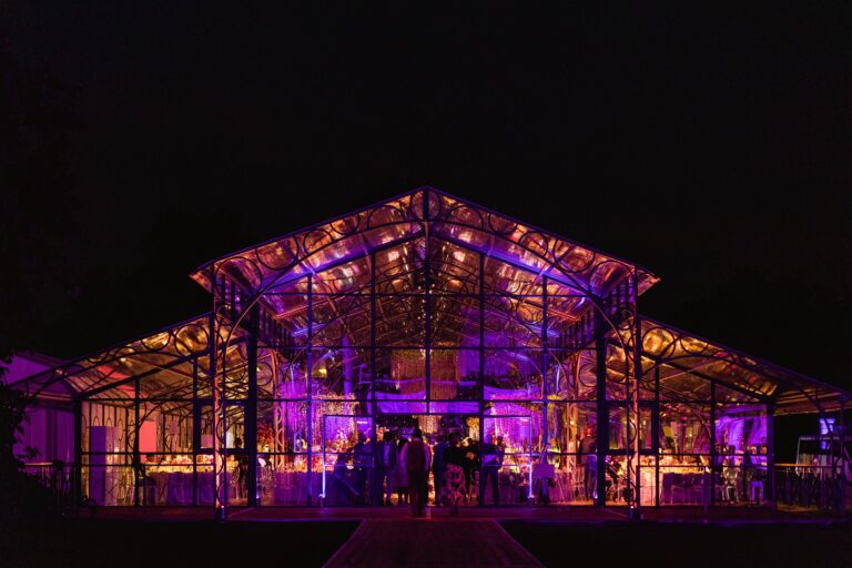 A glass marquee lit in purple and gold at night during an evening party, Cliveden House