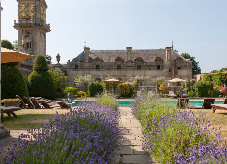The outdoor pool with lavender beds and parasols, and the clock tower behind, Cliveden House