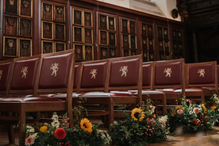Red leather chairs carved with a lion crest, with sunflowers and garden flowers along the aisle, Gray's Inn