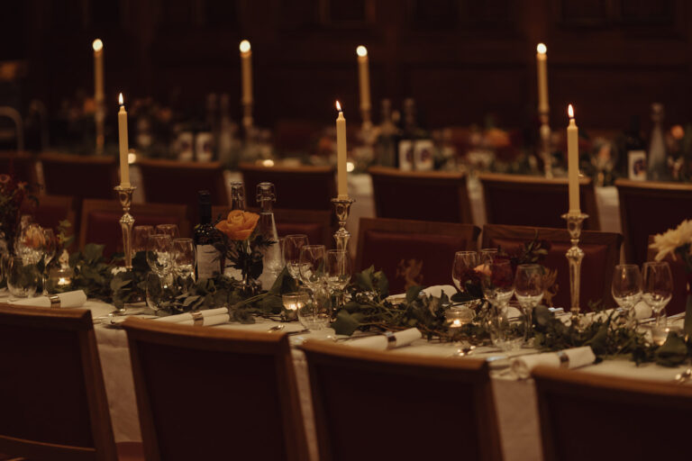 Tall candles and trailing greenery along a dinner table in low light, Gray's Inn