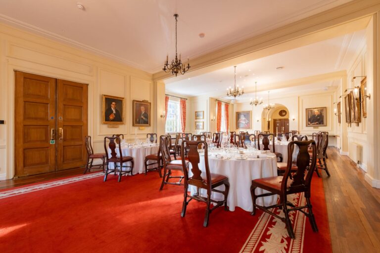 The Large Pension Room with round tables, a red carpet, chandeliers and tall windows, Gray's Inn