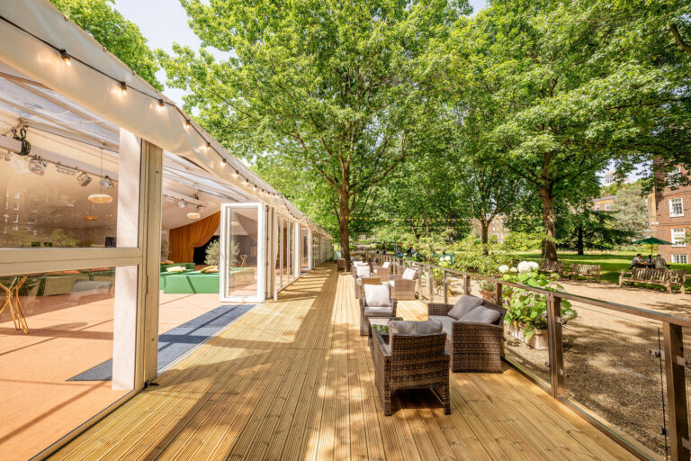 The timber terrace along the marquee, with lounge seating and trees overhead, Gray's Inn