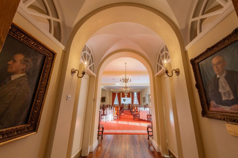 An arched passage hung with portraits, opening onto a room lit by a chandelier, Gray's Inn