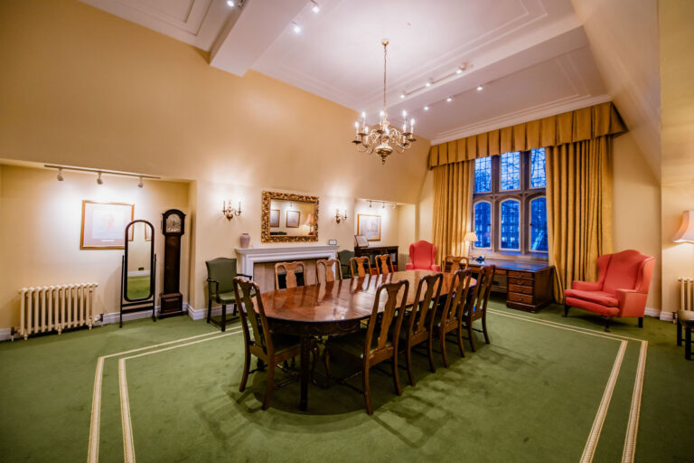 A long table in a high-ceilinged room with a green carpet, a fireplace and tall windows, Gray's Inn
