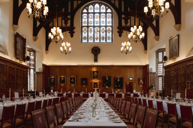 The Hall set for a wedding breakfast, with long white tables, red chairs and candles, Gray's Inn