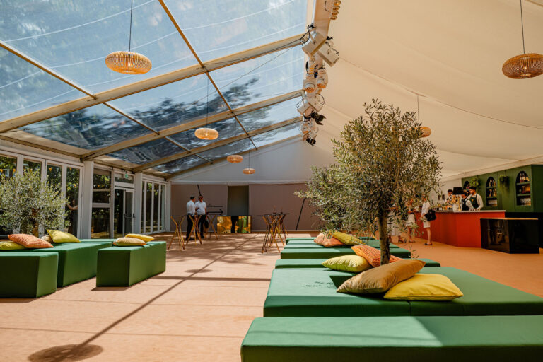 Inside the summer marquee, with a clear roof, green seating and potted olive trees, Gray's Inn