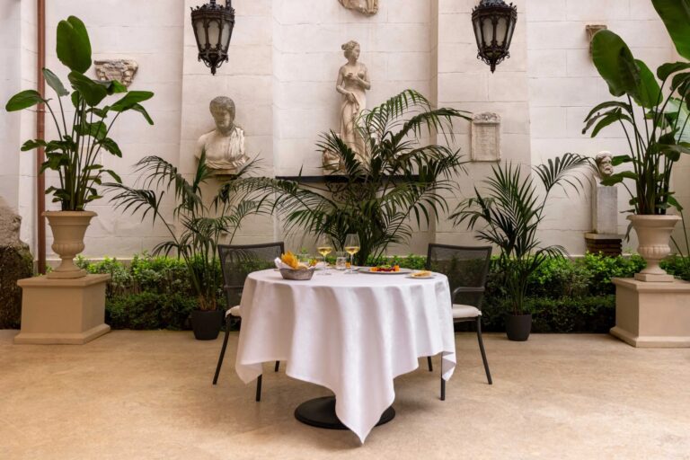 A table laid in the Palm Court garden, among palms and classical statues, Hassler Roma