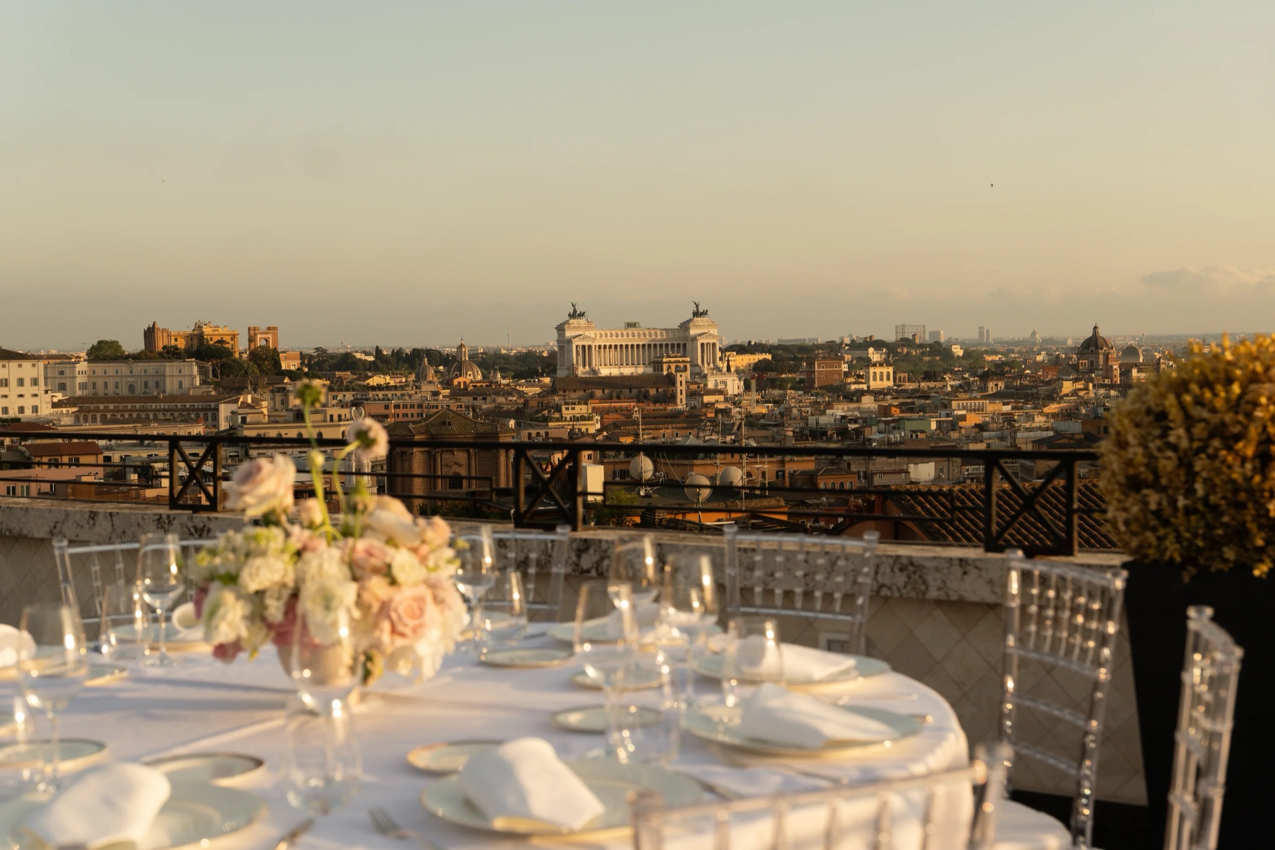 A round table laid for dinner on the Villa Medici Penthouse terrace, with the rooftops of Rome behind, Hassler Roma