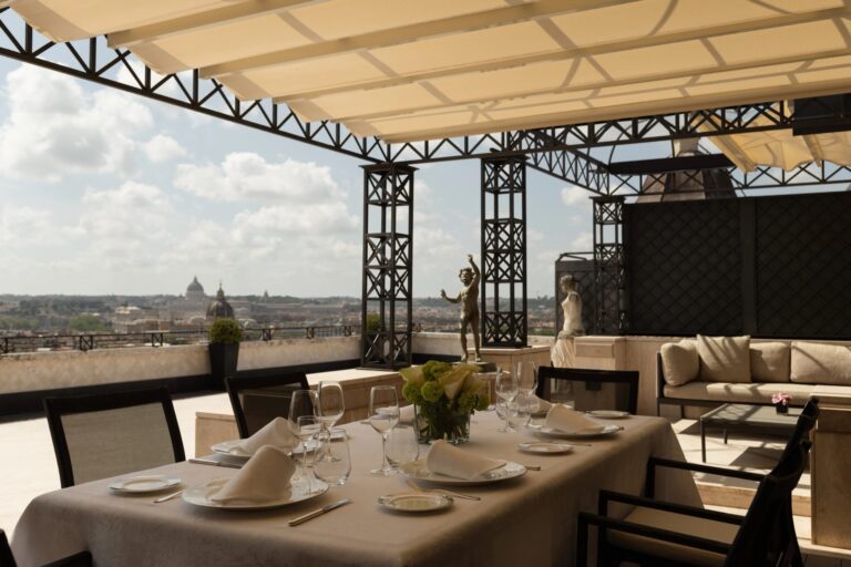 A table under the pergola of the Villa Medici Penthouse terrace, with the city beyond, Hassler Roma