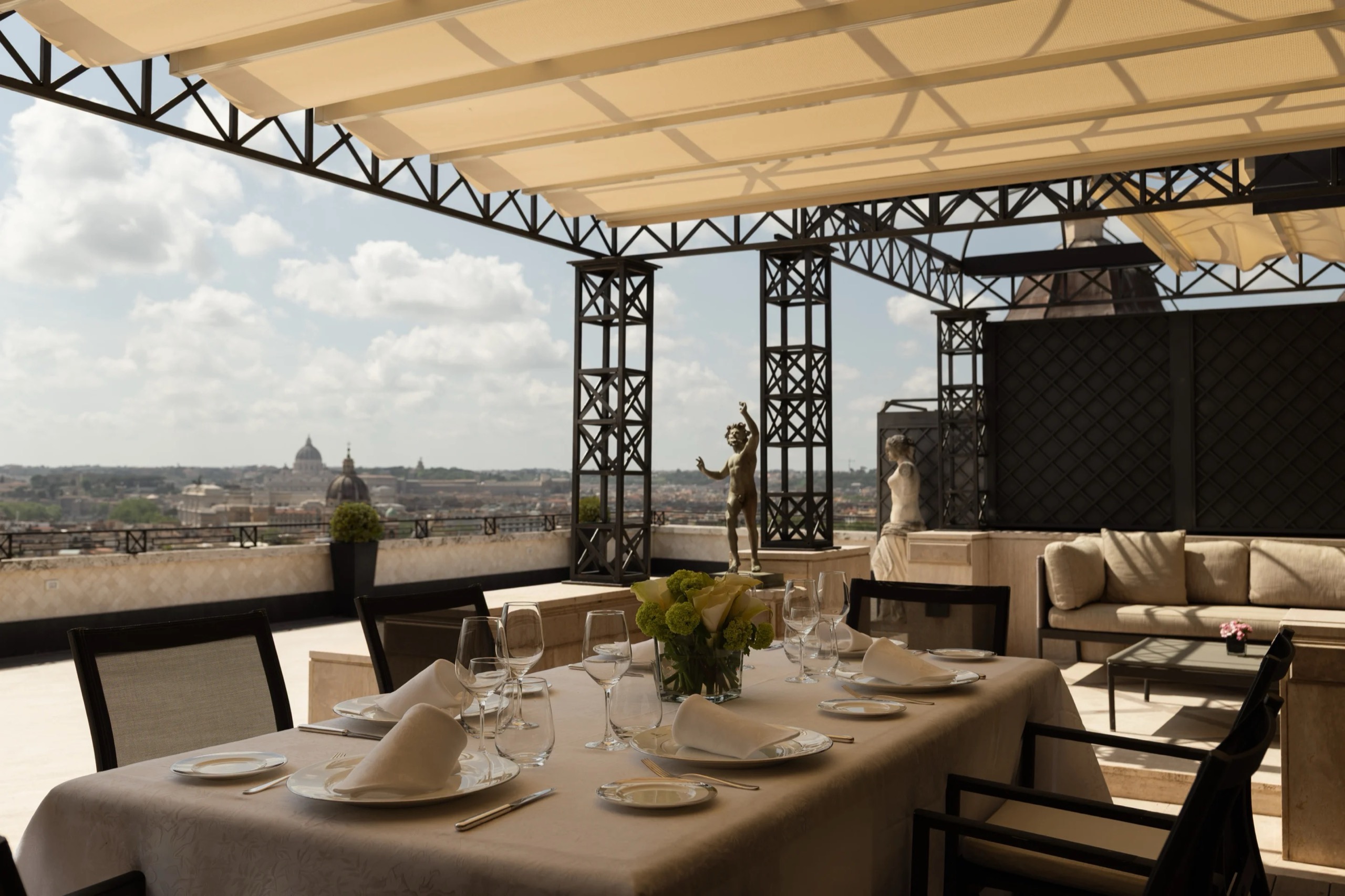 A table under the pergola of the Villa Medici Penthouse terrace, with the city beyond, Hassler Roma