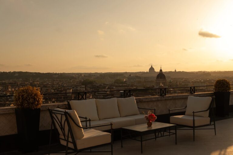 Outdoor sofas on the Villa Medici Penthouse terrace at sunset, looking over the rooftops of Rome, Hassler Roma