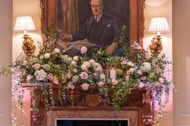 Pink and white flowers along a carved mantelpiece beneath a family portrait, Hedsor House