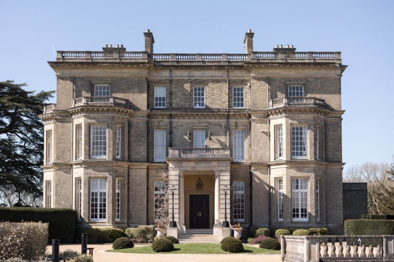 The entrance front, with its pillared porch, balustraded roofline and clipped box beside the gravel, Hedsor House