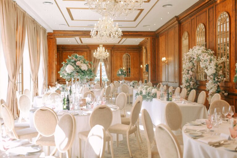 The Ballroom set for dinner in daylight, with a flower arch against the panelled wall, Hedsor House