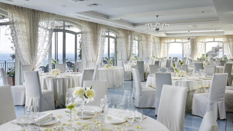 The Luna Vietrese hall laid with round tables and white chair covers, Hotel Raito