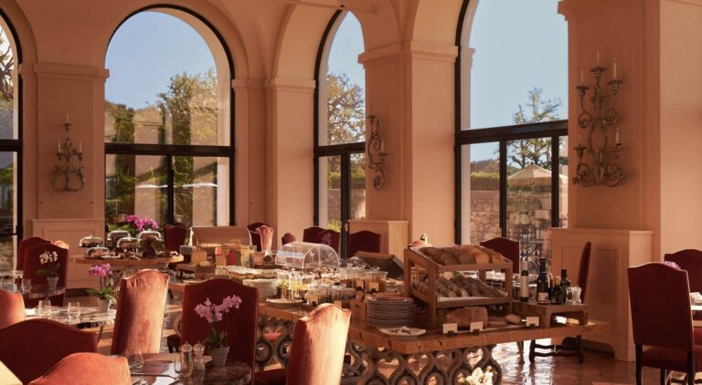The restaurant dining room under arched windows, laid for breakfast, La Posta Vecchia Hotel