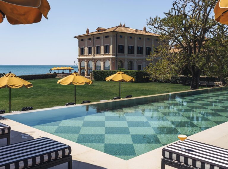 The outdoor pool in the gardens, with the villa and the sea behind, La Posta Vecchia Hotel