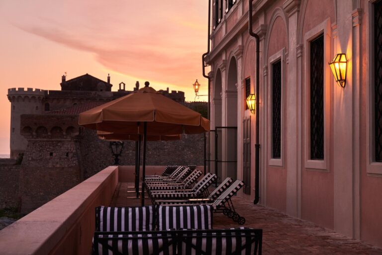 Sun loungers on a terrace at dusk, beside the castle walls, La Posta Vecchia Hotel