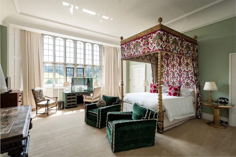 A Castle State bedroom with an embroidered four-poster bed, green velvet armchairs and tall leaded windows, Leeds Castle