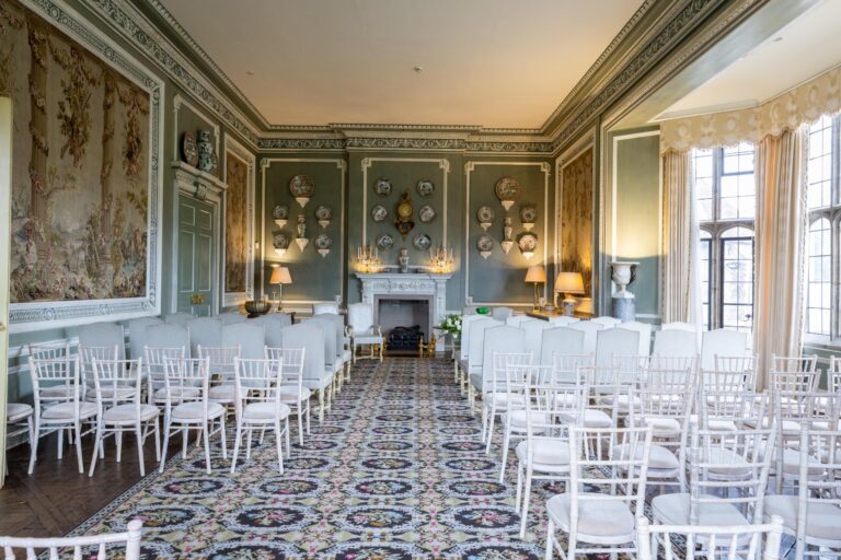 The Ceremony Room set with rows of white chairs, tapestry panels and a carved fireplace at the far end, Leeds Castle