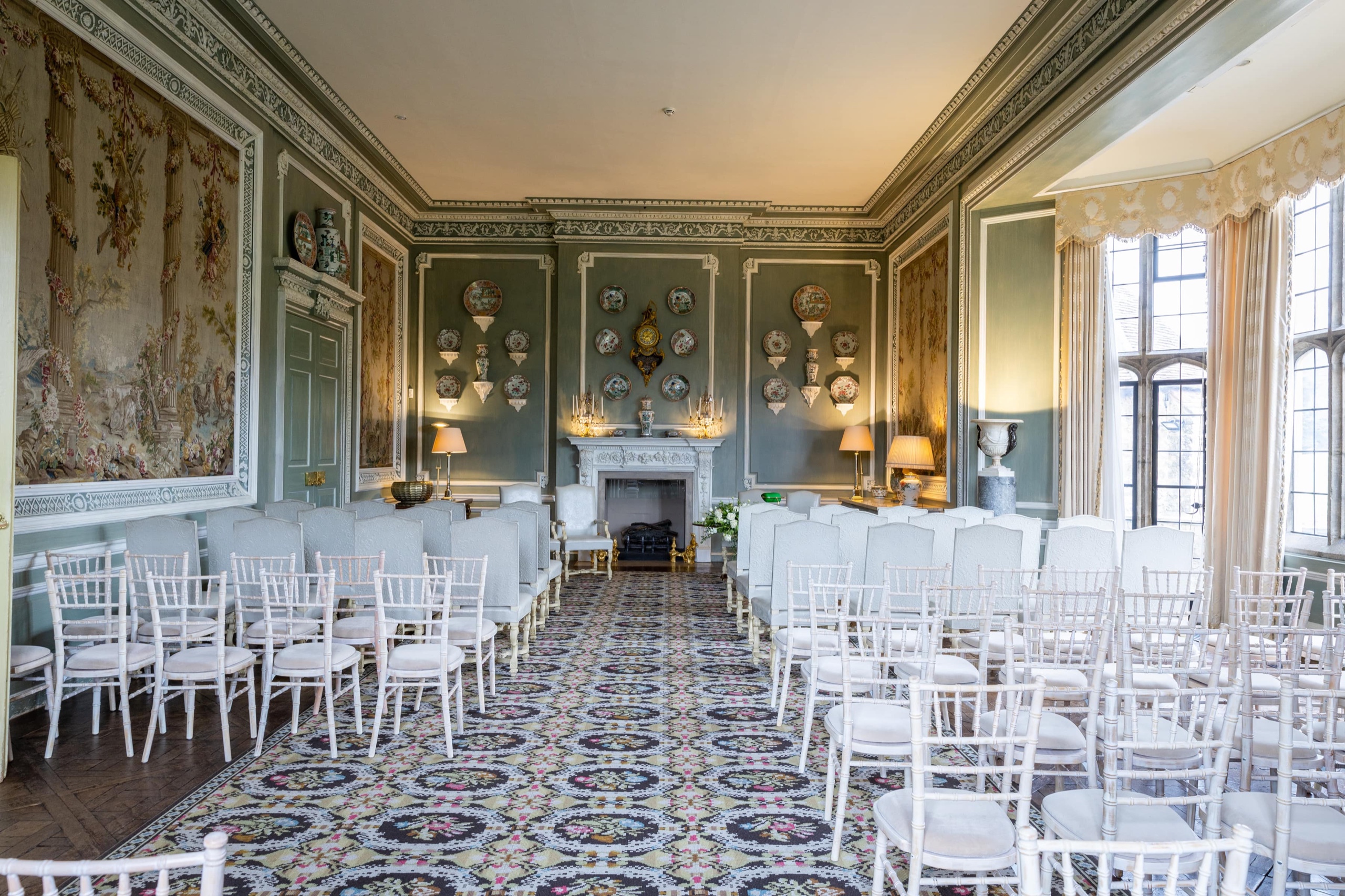 The Ceremony Room set with rows of white chairs, tapestry panels and a carved fireplace at the far end, Leeds Castle