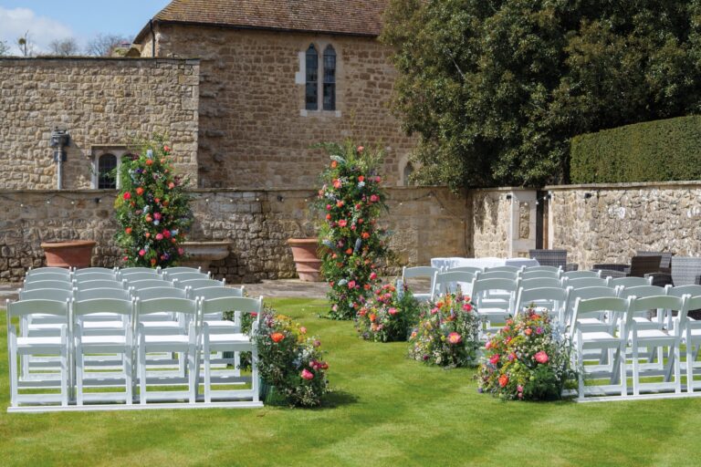 Maiden's Tower private garden laid out for a ceremony, with floral columns against the old stone walls, Leeds Castle