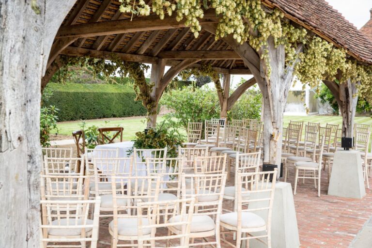 The timber-framed garden pagoda at Battel Hall hung with hops and set with chairs for a small ceremony, Leeds Castle