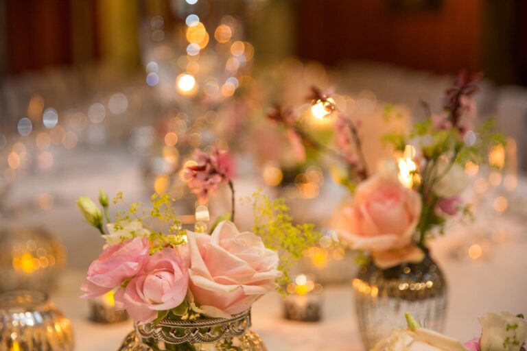 Pink roses in small mercury-glass vases among tea lights on a reception table, Leeds Castle